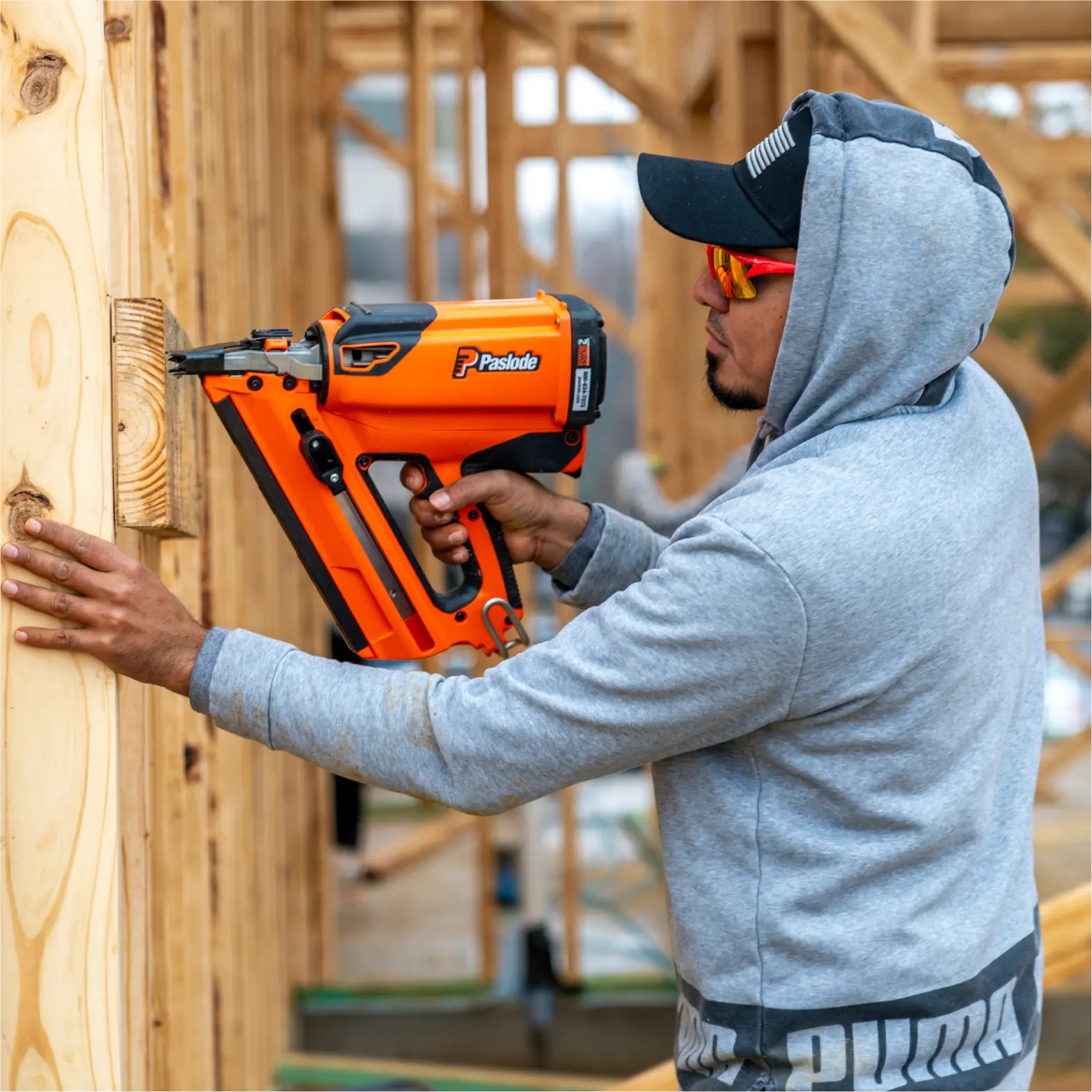 Framer using a Paslode nail gun on a wall frame